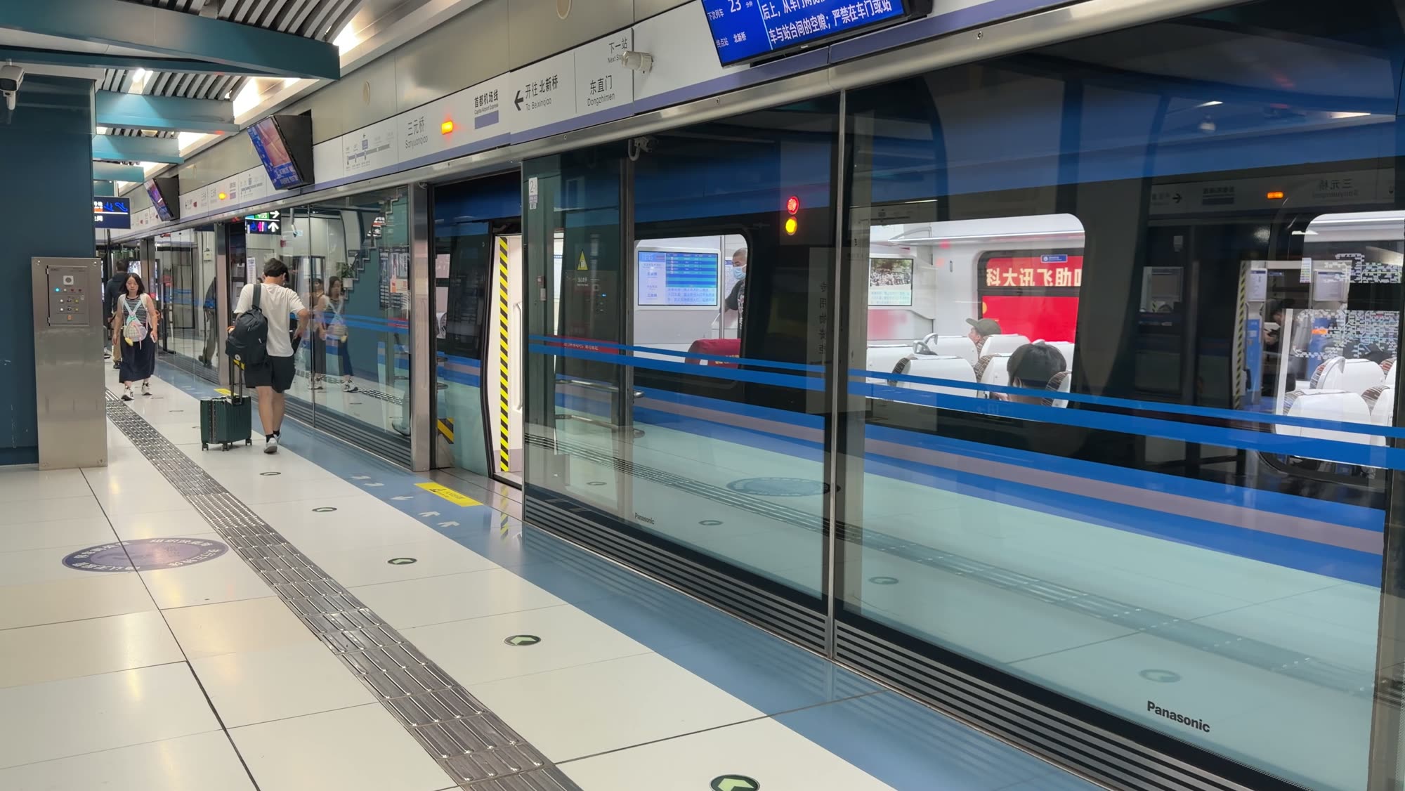 The Airport Express platform at Beijing Capital Airport, blue and white train behind glass platform doors