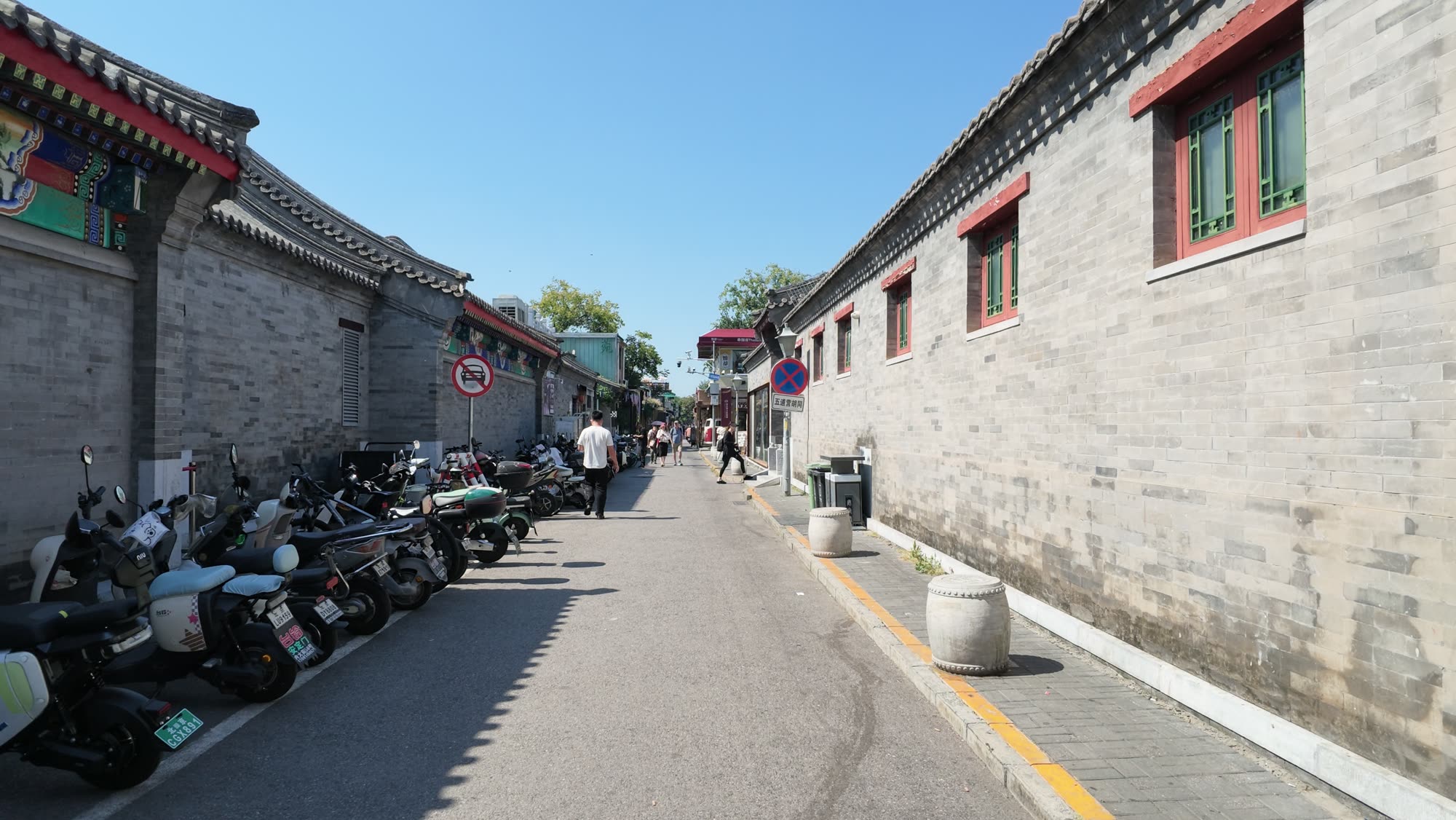 A quiet grey-brick hutong lane near Wudaoying, with scooters parked along the wall